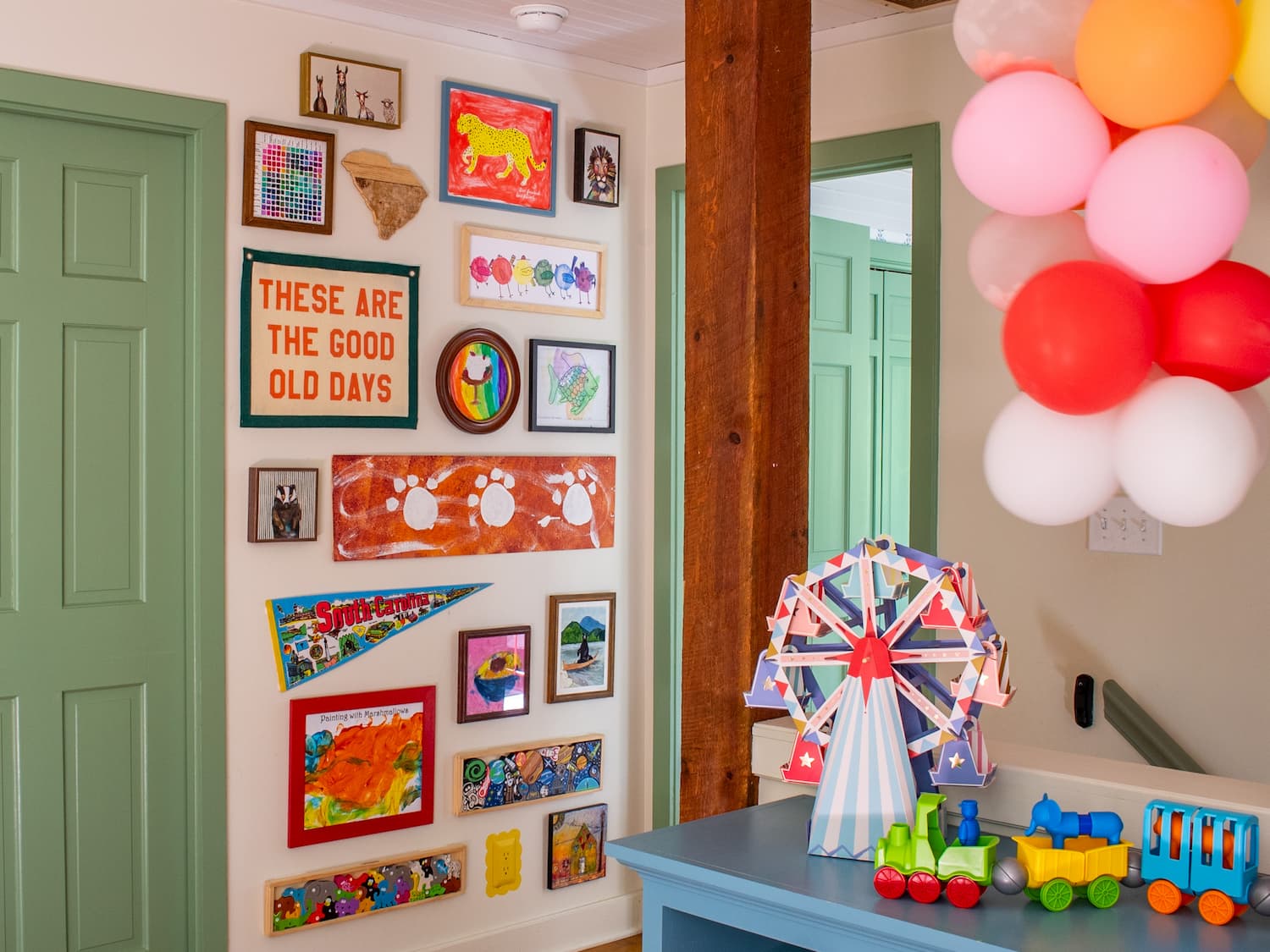 colorful-gallery-wall-playroom Colorful gallery wall in a playroom featuring a mix of art. Toys and balloons are off to the side.