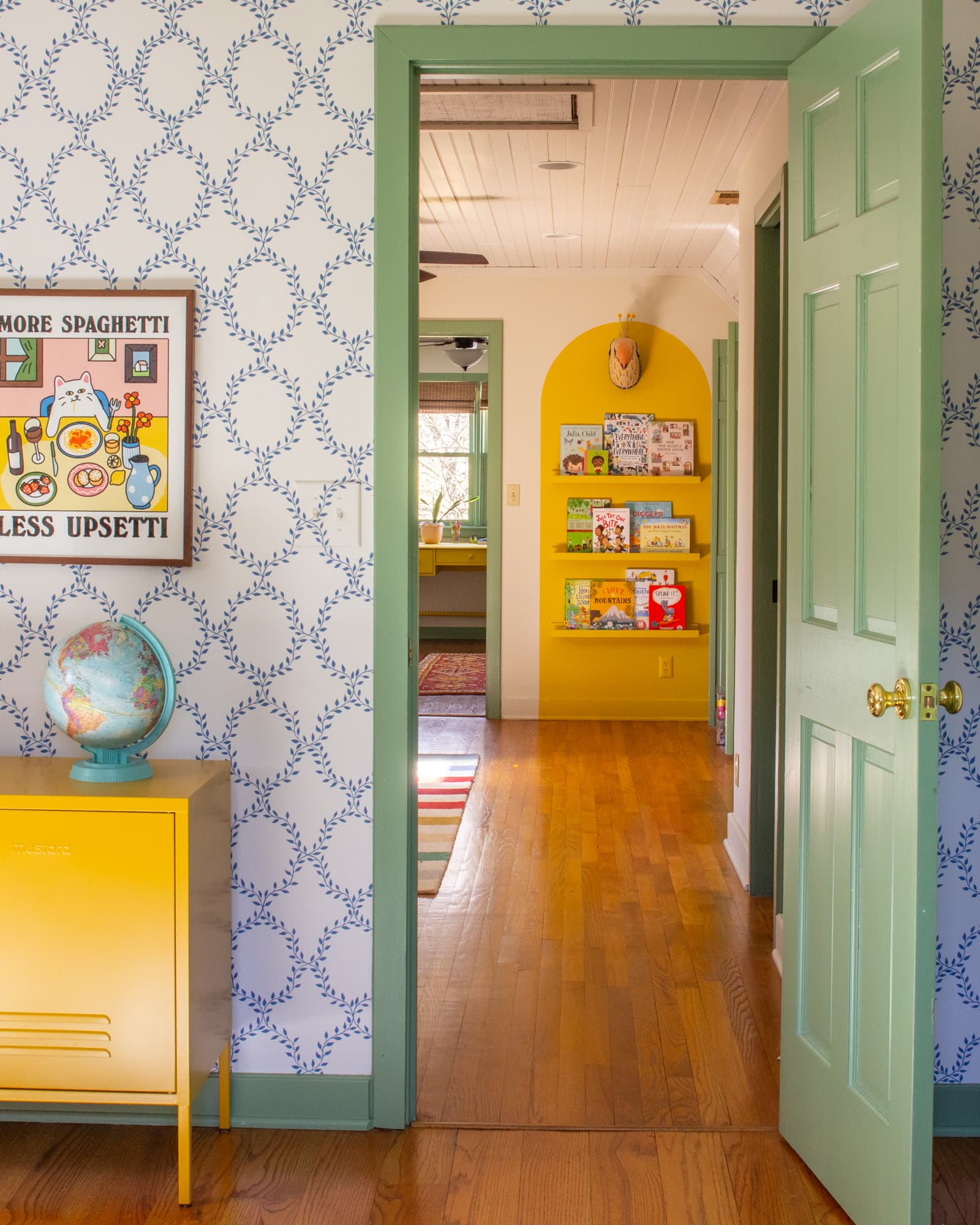 Doorway leading out of a kids bedroom to a playroom. An arch wall with bookshelves is seen through the door