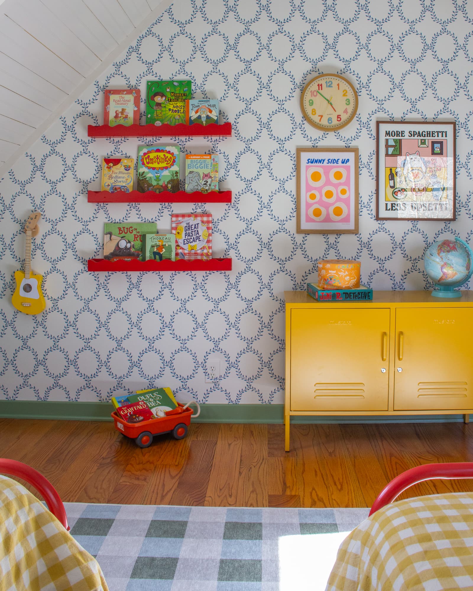 Wall of art in a child's bedroom featuring a few book shelves and a yellow locker-style cabinet