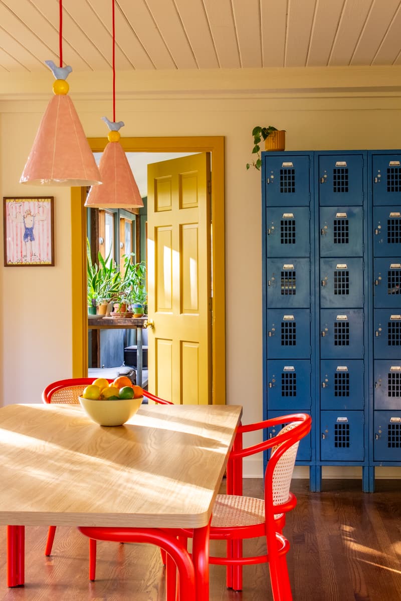 Colorful dining room with pink pendants, red chairs, yellow trim and a blue locker