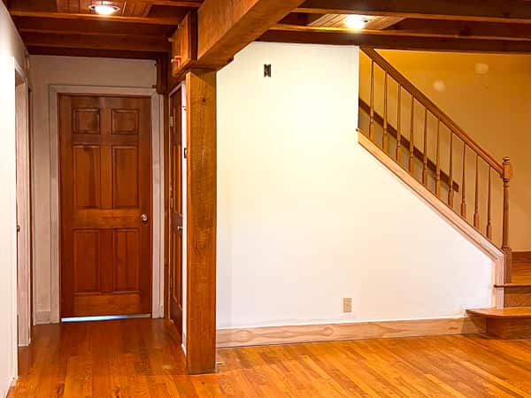 Before photo of an entryway wall under stairs