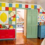 Colorful kids room with checkered wall, colorful art, blue dresser, green door and red cabinet.