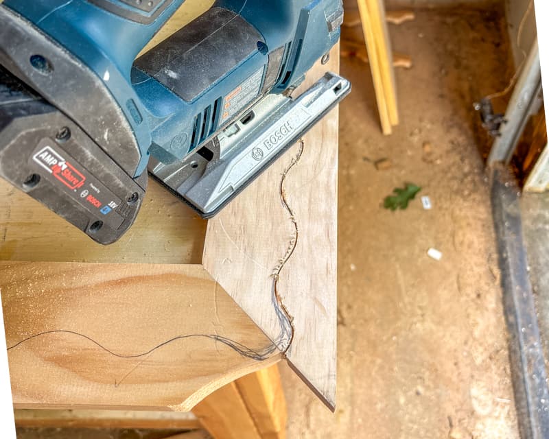 Overhead shot showing a jigsaw on top of a piece of wood that needs to be cut with wavy pencil marks